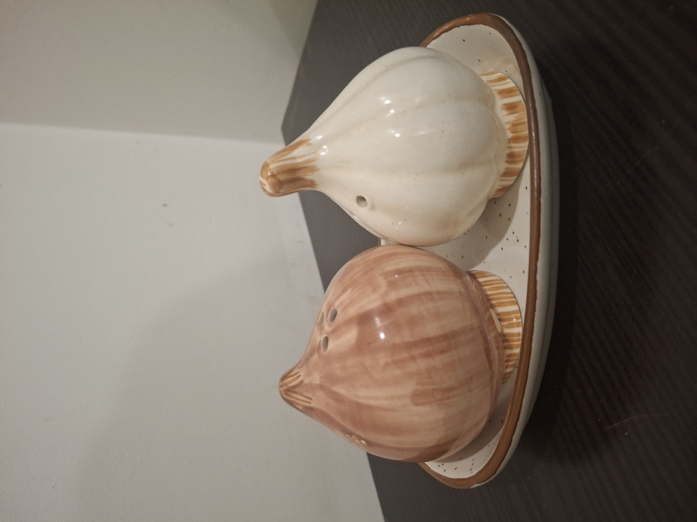 Garlic and onion ceramic salt and pepper shakers on a speckled tray